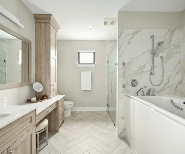 Accessible bathroom remodel in Wilmington, NC with a grab bar by the tub, a handheld shower and a seated vanity