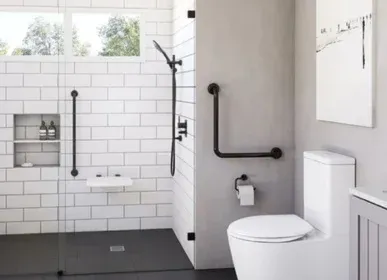 White subway tile shower with black grab bars, a fold-down seat and a comfort-height toilet
