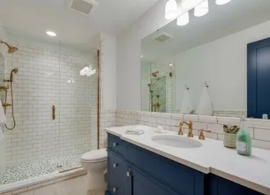 Navy vanity, white subway tile and a glass shower with brass fixtures