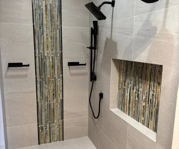 Large-format porcelain shower tile with a vertical mosaic stripe and a matching niche