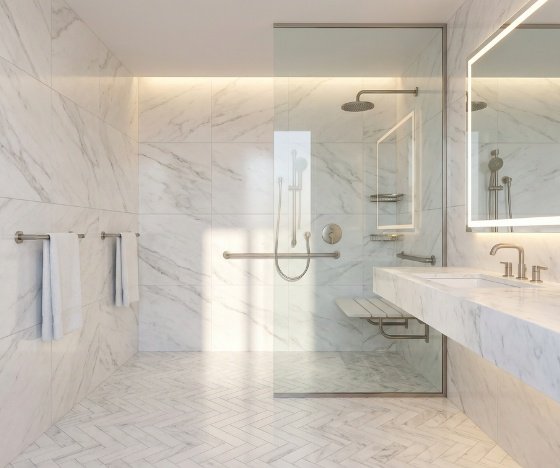 ADA-accessible bathroom remodel in Wilmington, NC featuring marble tile, grab bars, a fold-down shower seat, and a frameless glass enclosure.