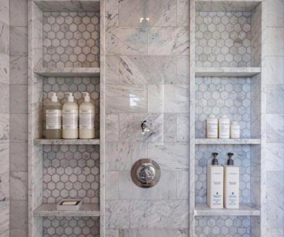 Custom shower niches in a Wilmington, NC bathroom remodel featuring marble tile and hexagon accent shelving.