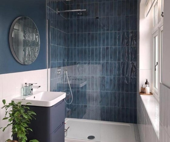 Bathroom remodel in Wilmington, NC featuring a walk-in shower with deep blue vertical tile, a rainfall showerhead, and a modern navy vanity.
