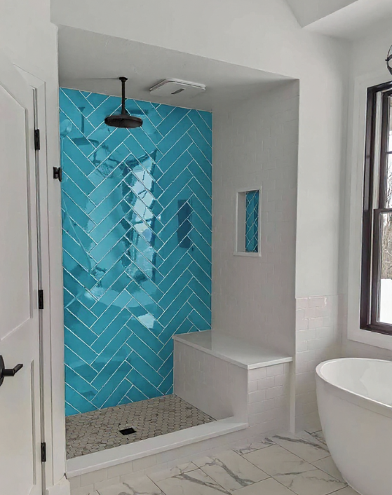Bathroom remodel in Wilmington, NC featuring a walk-in shower with vibrant aqua herringbone tile, built-in bench, and modern subway tile accents.