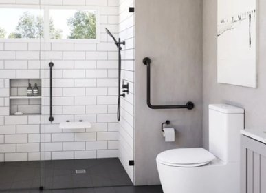 ADA-accessible bathroom remodel in Wilmington, NC featuring a walk-in shower with grab bars, a fold-down seat, and modern black fixtures.