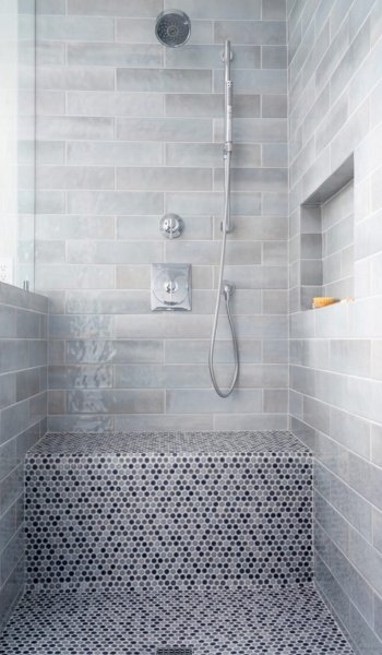 Custom tile shower remodel in Wilmington, NC featuring a built-in bench, handheld showerhead, and mosaic tile flooring.